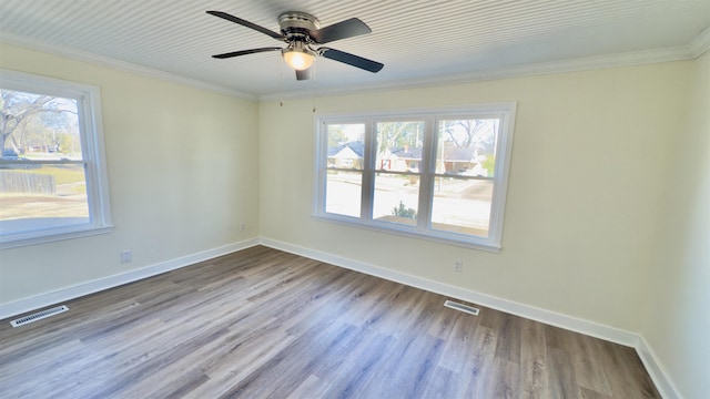 spare room featuring wood finished floors, visible vents, and baseboards