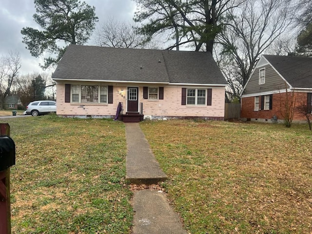 view of front of home with brick siding, a front yard, and roof with shingles