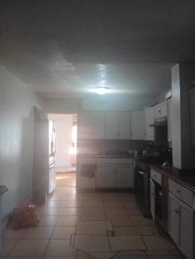 kitchen featuring under cabinet range hood, light tile patterned floors, appliances with stainless steel finishes, white cabinetry, and a sink