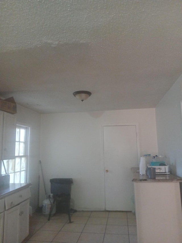 interior space featuring white cabinetry, light countertops, light tile patterned floors, and a textured ceiling