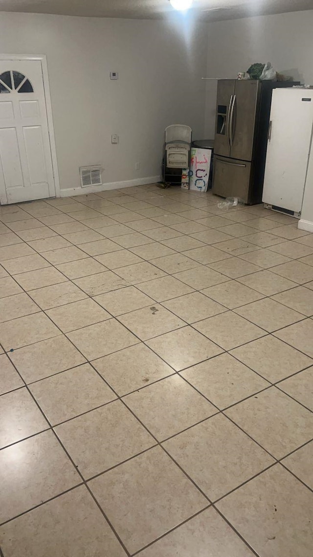 empty room featuring light tile patterned floors, visible vents, and baseboards