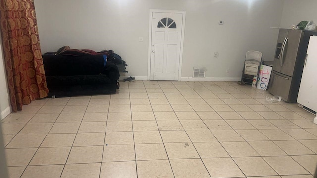 unfurnished room featuring light tile patterned floors, visible vents, and baseboards