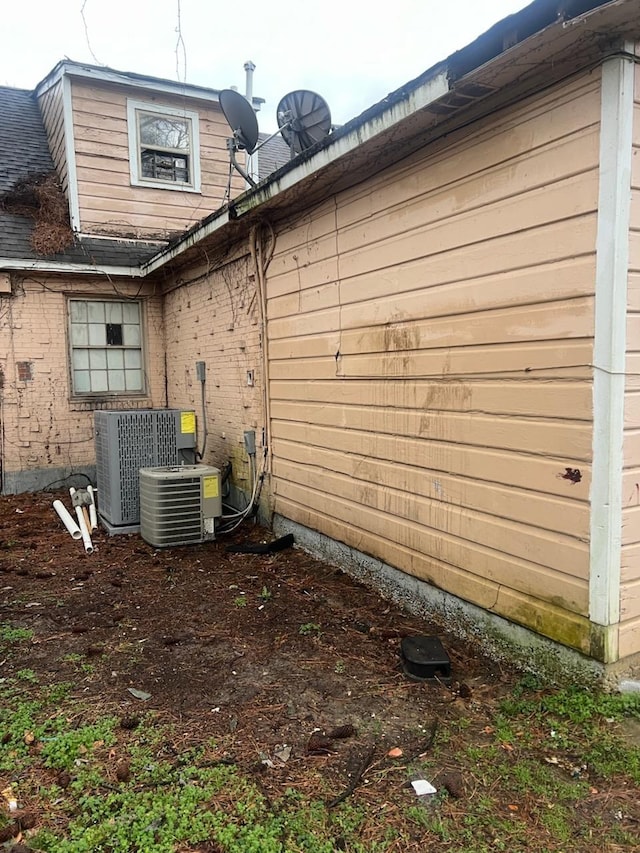 view of home's exterior with cooling unit and a shingled roof