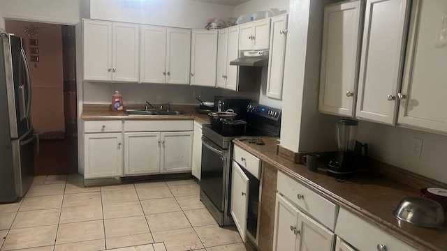 kitchen featuring electric range, under cabinet range hood, a sink, freestanding refrigerator, and light tile patterned floors