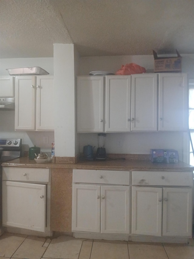 kitchen featuring ventilation hood, stove, and white cabinetry