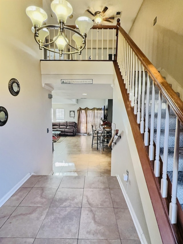 staircase featuring tile patterned flooring, a notable chandelier, and baseboards