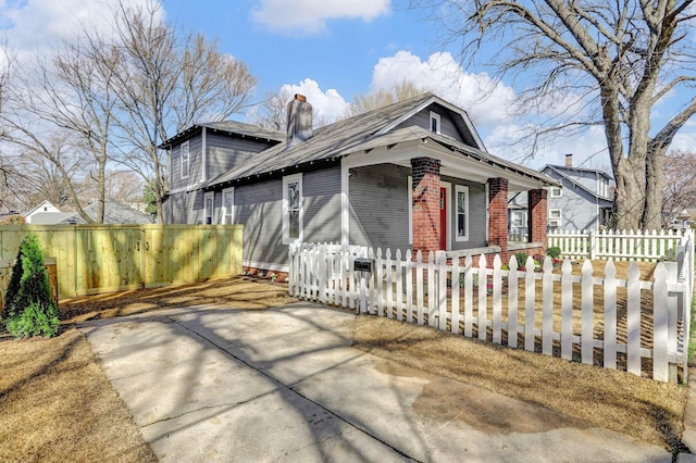 view of front of property featuring a fenced front yard, a chimney, and brick siding