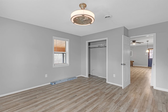 unfurnished bedroom featuring visible vents, multiple windows, and wood finished floors