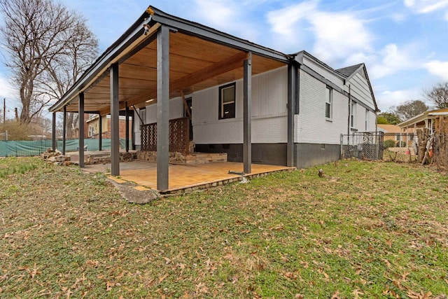 back of property with crawl space, a lawn, brick siding, and fence