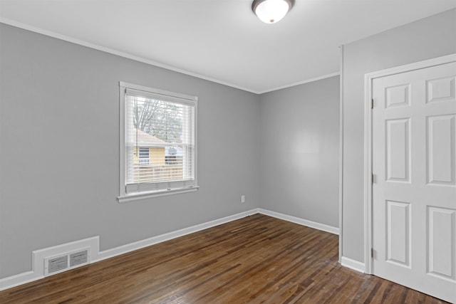 empty room featuring visible vents, crown molding, dark wood-type flooring, and baseboards