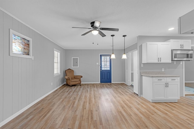 kitchen featuring stainless steel microwave, a ceiling fan, light wood-style flooring, and white cabinets