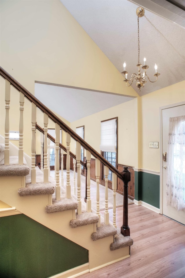 foyer featuring stairway, an inviting chandelier, wood finished floors, and vaulted ceiling