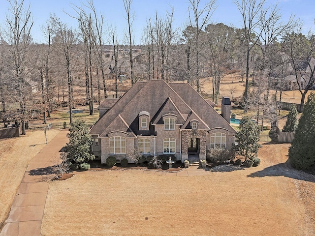 french country style house with fence and brick siding