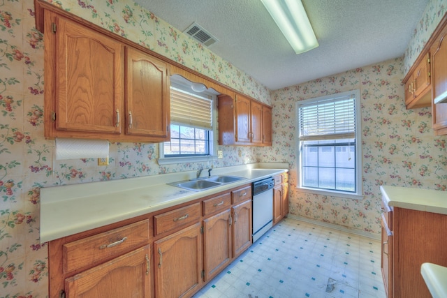 kitchen featuring visible vents, a sink, white dishwasher, wallpapered walls, and light floors