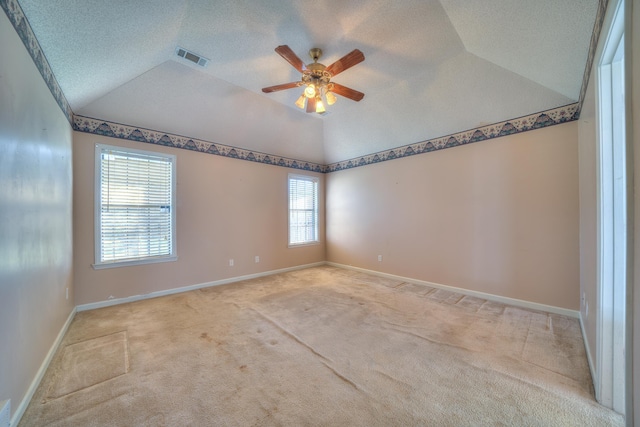 empty room featuring carpet, baseboards, visible vents, lofted ceiling, and a textured ceiling