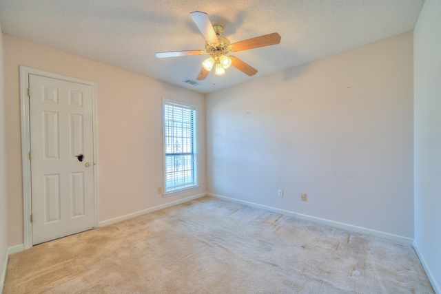 spare room featuring baseboards, light colored carpet, visible vents, and a textured ceiling