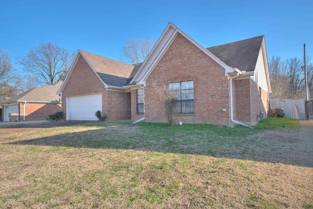 view of front of property with a front lawn, brick siding, an attached garage, and fence