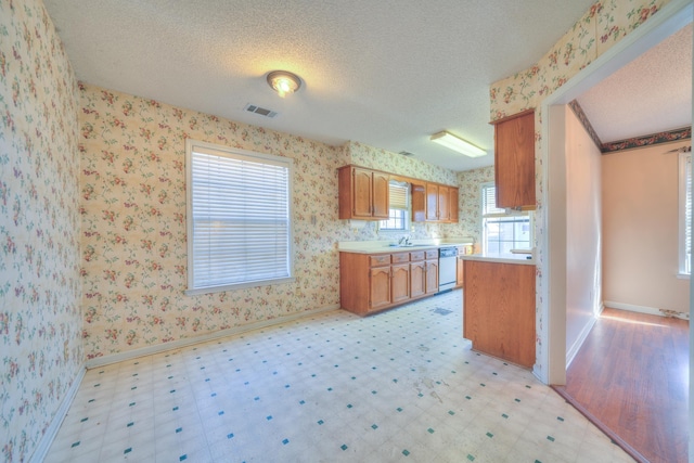 kitchen featuring light floors, dishwasher, and wallpapered walls