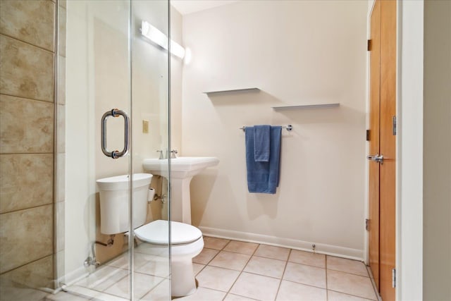 bathroom with baseboards, toilet, a shower stall, and tile patterned flooring