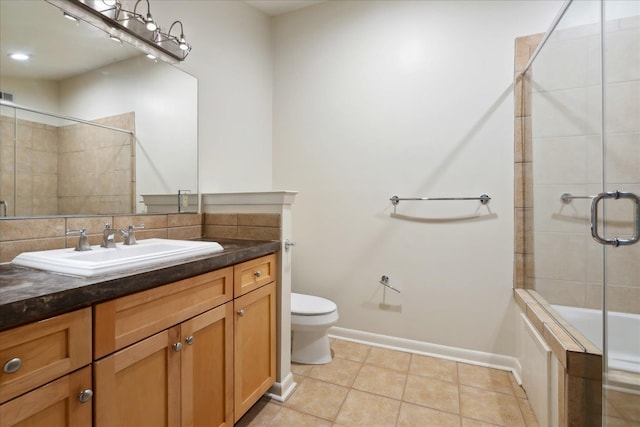 bathroom with vanity, baseboards, tile patterned floors, toilet, and tiled shower / bath