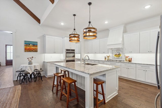 kitchen featuring dark wood finished floors, double oven, decorative backsplash, custom exhaust hood, and a sink