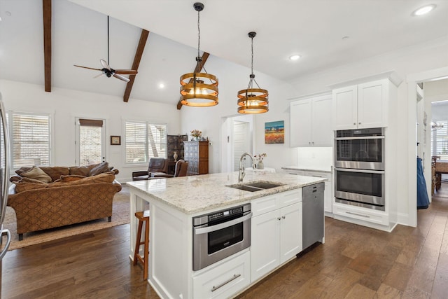 kitchen featuring a sink, open floor plan, appliances with stainless steel finishes, vaulted ceiling with beams, and dark wood-style flooring