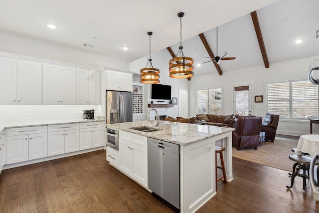 kitchen with dark wood-style floors, appliances with stainless steel finishes, a kitchen island with sink, and a sink