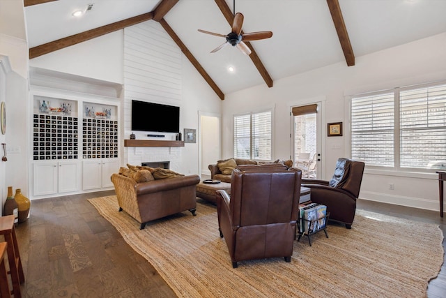 living area featuring beam ceiling, high vaulted ceiling, a ceiling fan, wood finished floors, and a fireplace