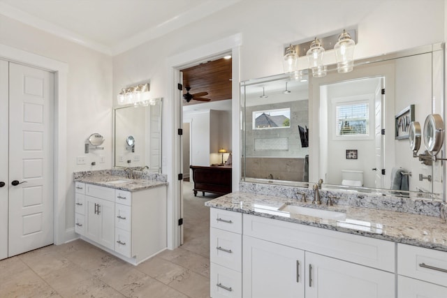 bathroom featuring ceiling fan, two vanities, tiled shower, and a sink