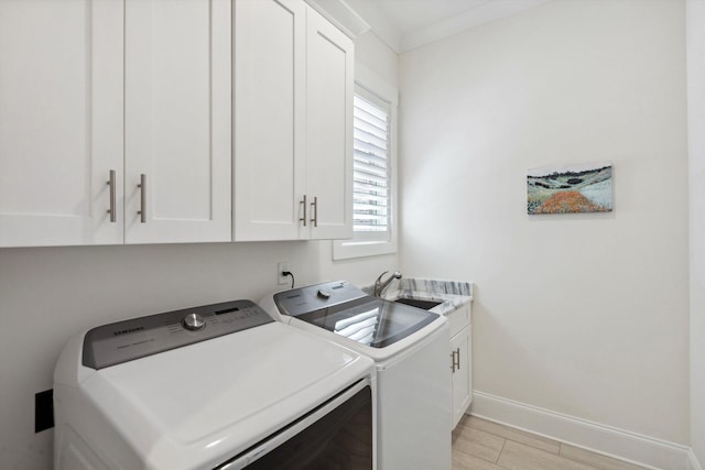 laundry area featuring light wood finished floors, baseboards, washer and dryer, cabinet space, and a sink