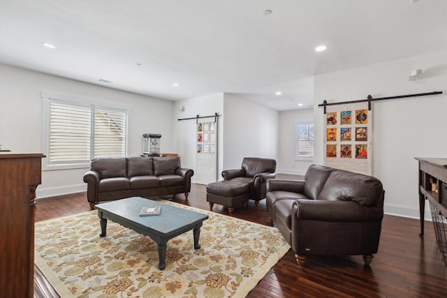 living area with a barn door, recessed lighting, dark wood-style flooring, and baseboards