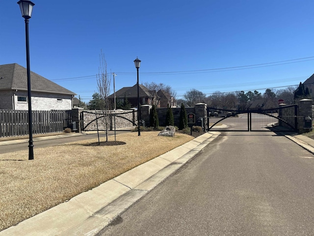 view of street featuring curbs, a gated entry, street lighting, and a gate