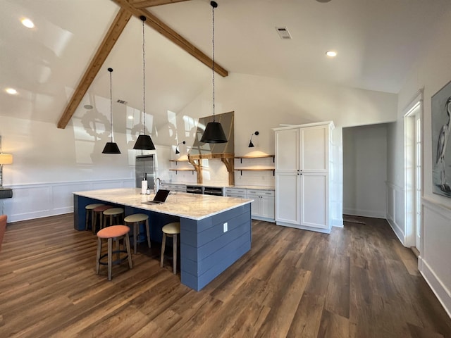 kitchen with dark wood finished floors, beamed ceiling, a wainscoted wall, white cabinetry, and built in fridge