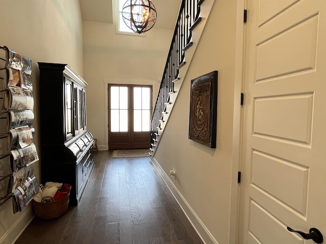 entryway with stairway, baseboards, an inviting chandelier, dark wood-style flooring, and a towering ceiling