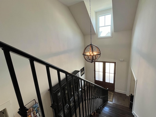 stairs featuring plenty of natural light, baseboards, an inviting chandelier, and wood finished floors