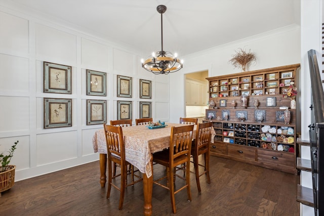 dining space featuring dark wood-type flooring, a decorative wall, a notable chandelier, and ornamental molding