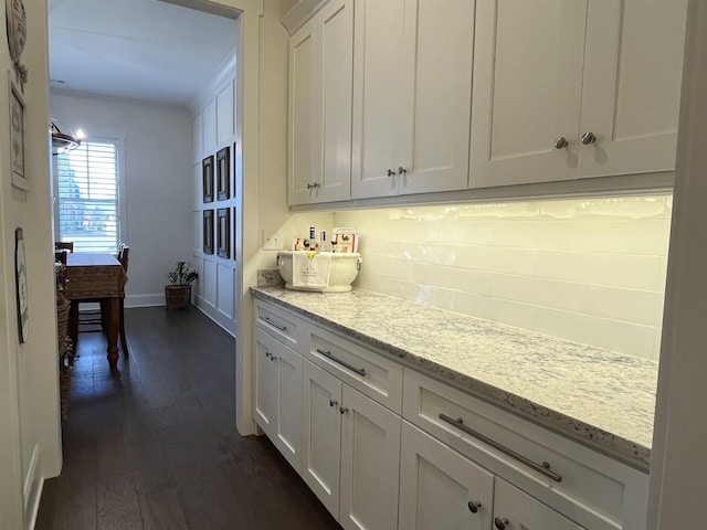 kitchen featuring dark wood-type flooring, baseboards, ornamental molding, light stone counters, and white cabinets