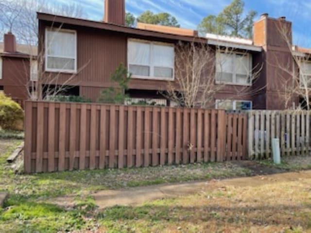 rear view of house featuring a chimney and fence