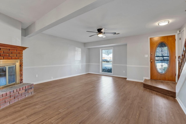 unfurnished living room with visible vents, ceiling fan, baseboards, a fireplace, and wood finished floors