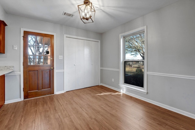 foyer entrance with visible vents, light wood-style flooring, baseboards, and an inviting chandelier