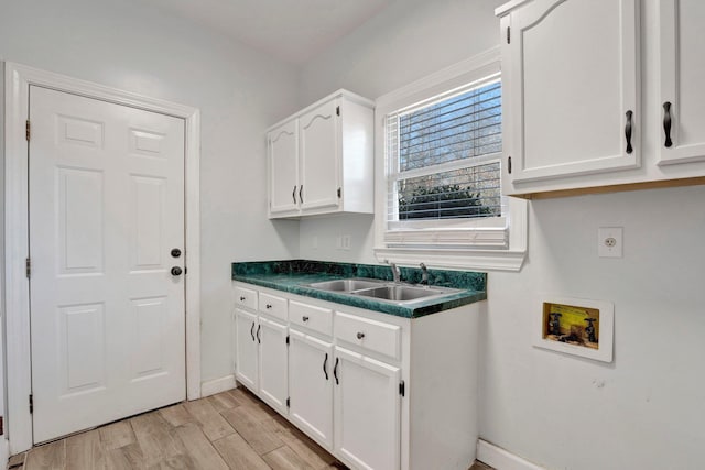 laundry room featuring light wood finished floors, baseboards, hookup for a washing machine, cabinet space, and a sink