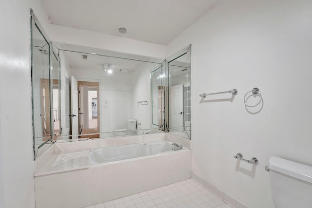 bathroom with tile patterned flooring, a garden tub, toilet, and baseboards