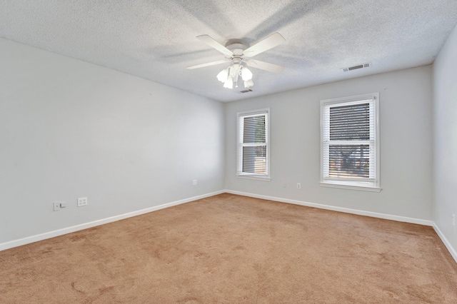 carpeted empty room featuring visible vents, a textured ceiling, baseboards, and a ceiling fan