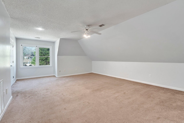 bonus room featuring vaulted ceiling, light carpet, baseboards, and a textured ceiling