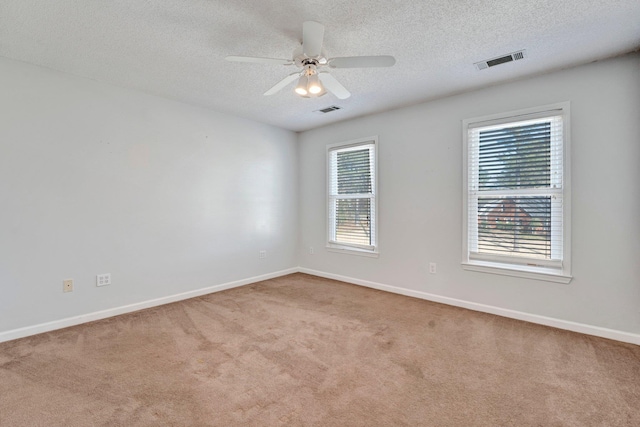 carpeted spare room with baseboards, a ceiling fan, visible vents, and a textured ceiling