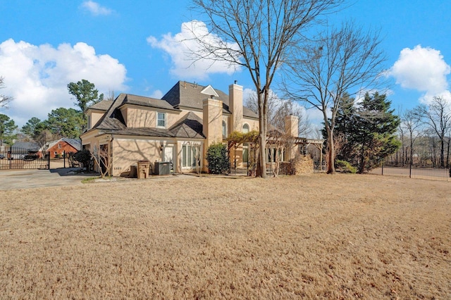 view of side of home with fence, stucco siding, cooling unit, a chimney, and a yard