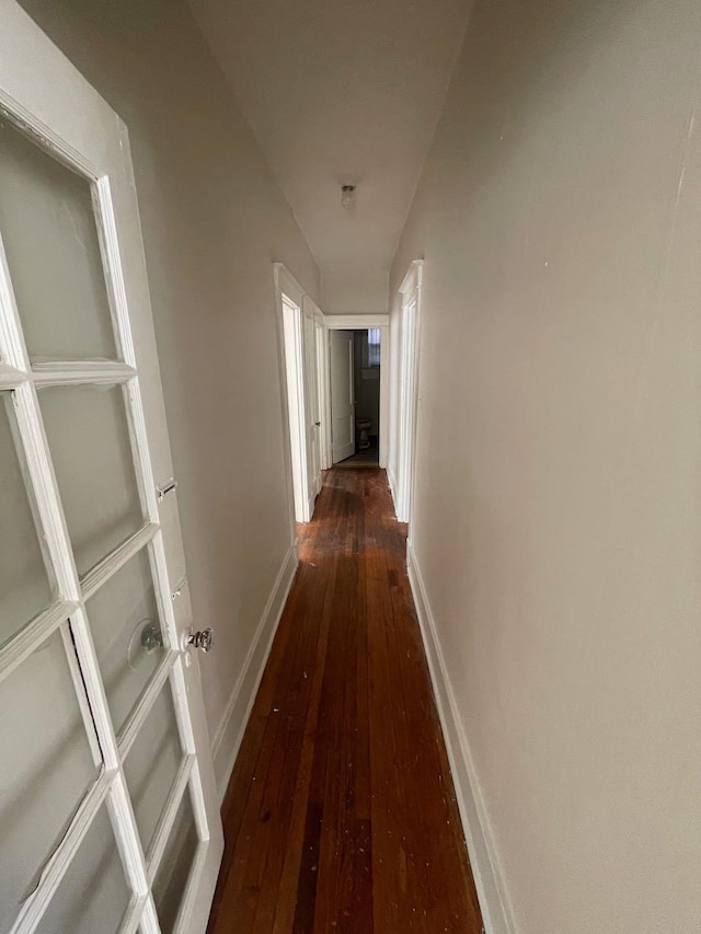 corridor featuring baseboards and hardwood / wood-style flooring