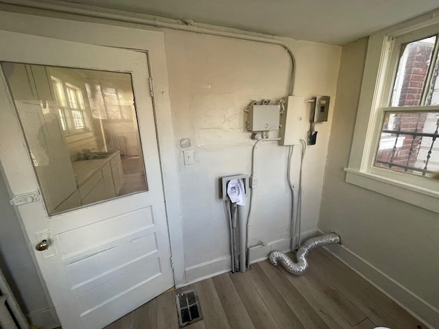 laundry room with wood finished floors, visible vents, and baseboards