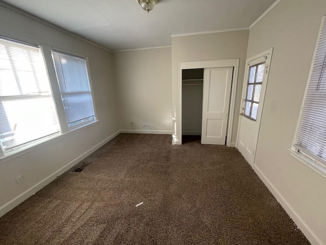 unfurnished bedroom with multiple windows, baseboards, dark colored carpet, and ornamental molding