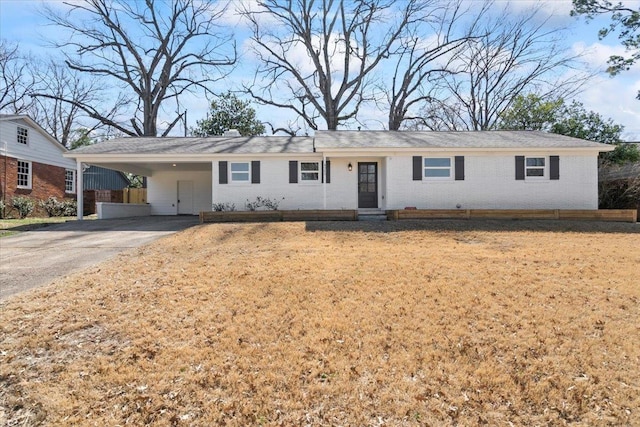 ranch-style home with a carport, a front yard, brick siding, and driveway